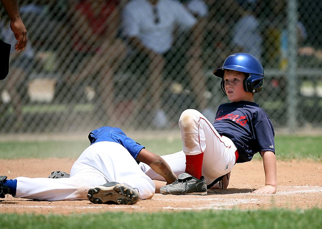 Young baseball players in action during an intense game at a sunlit field.