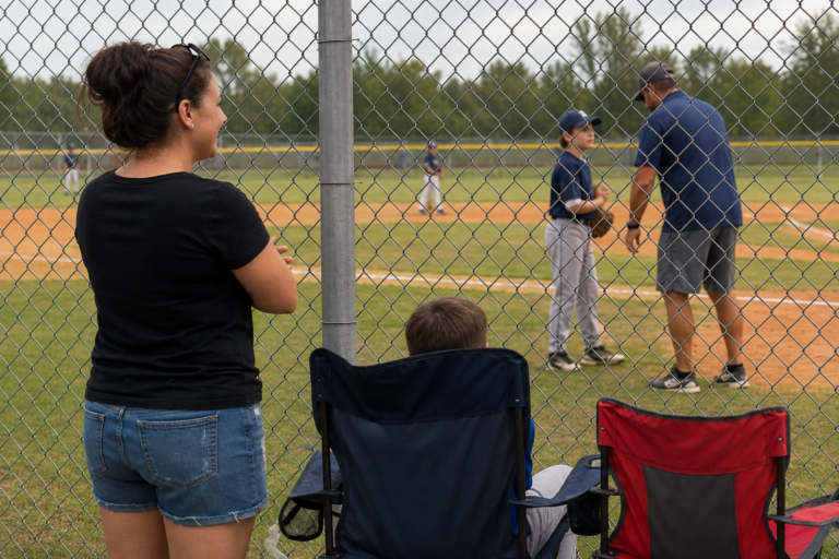 Parent watching and supporting a player during a travel baseball game